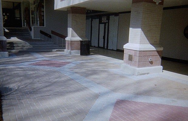A brick walkway leading to a building with columns and stairs