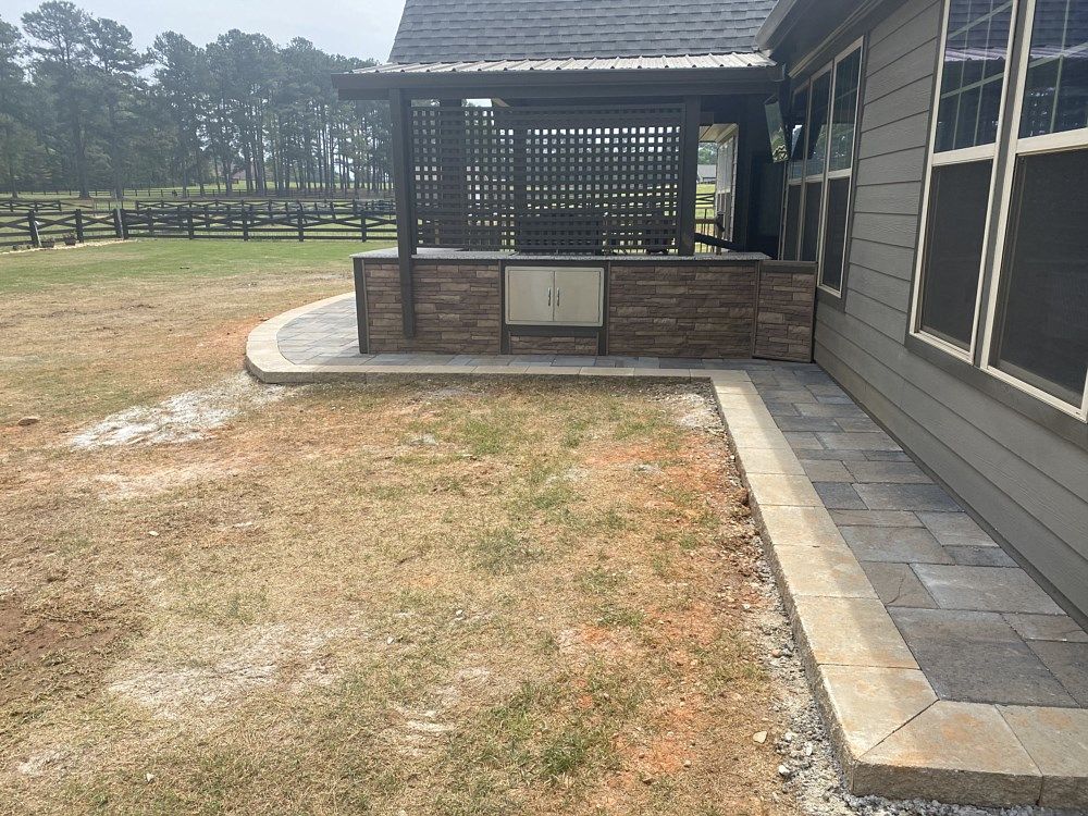 The backyard of a house with a patio and a grill.