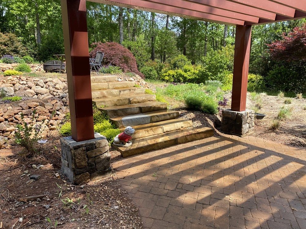 A pergola with stairs leading up to it in a garden.