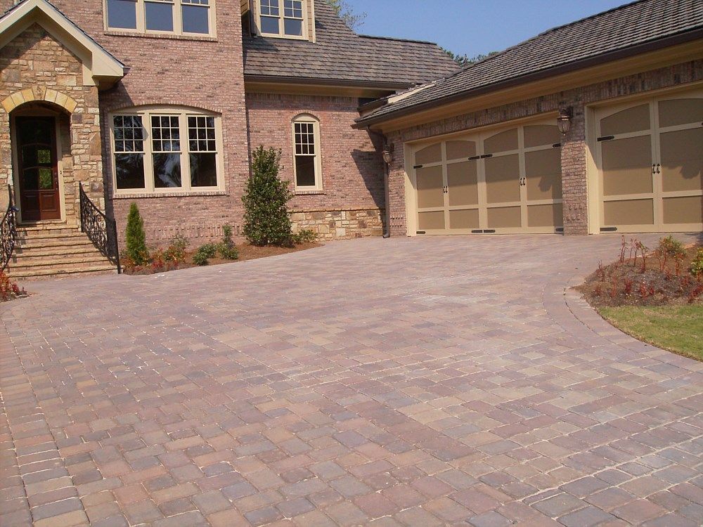 A large brick house with a brick driveway in front of it