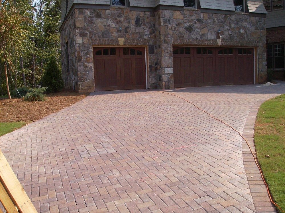 A brick driveway leading to a house with two garage doors