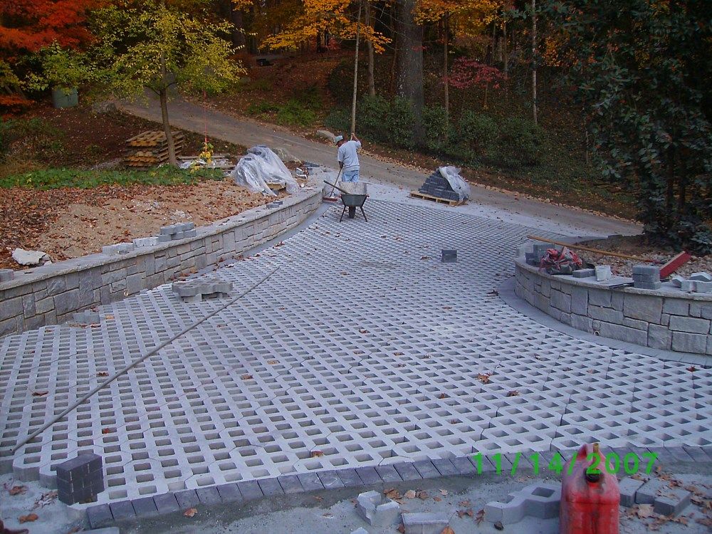 A man is pushing a wheelbarrow down a concrete driveway