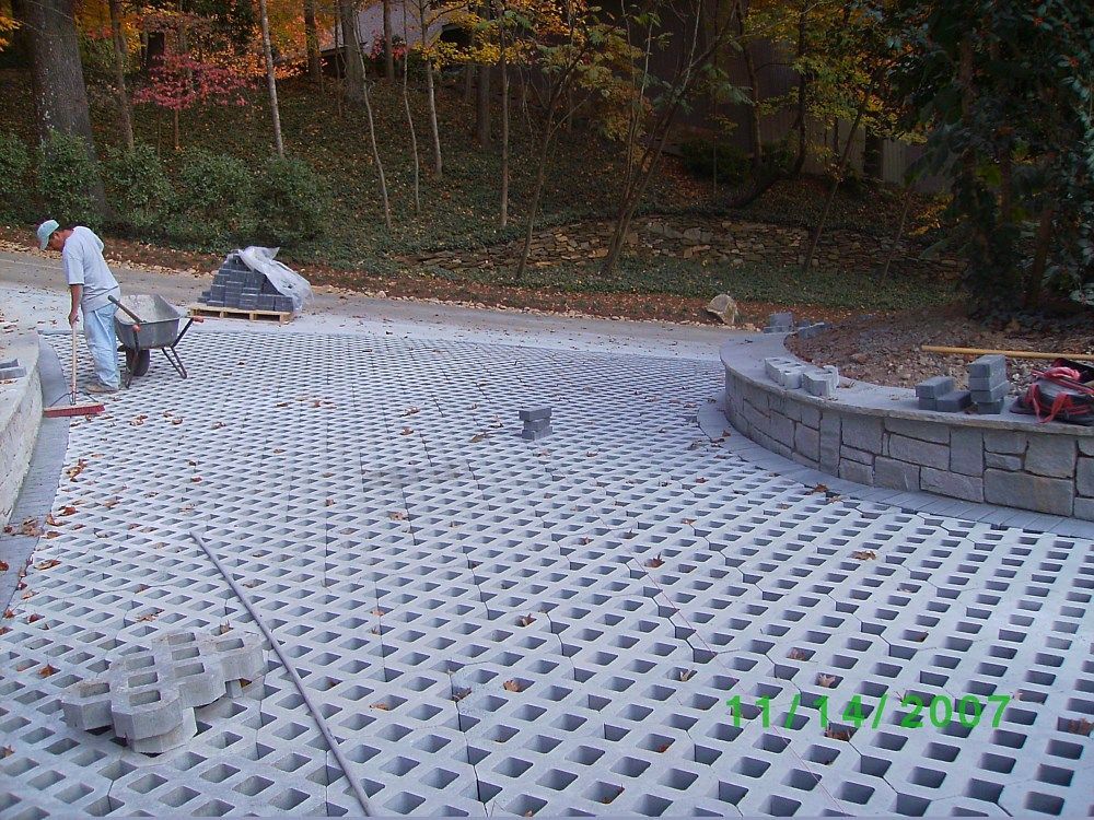 A man is pushing a wheelbarrow down a concrete driveway.