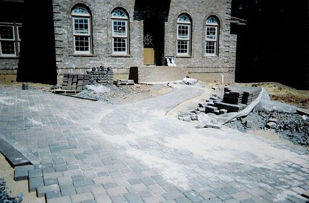 A brick driveway is being built in front of a large brick building.
