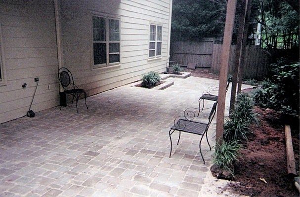 A patio with chairs and a table in front of a house.