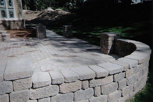 A stone wall with a patio in the background