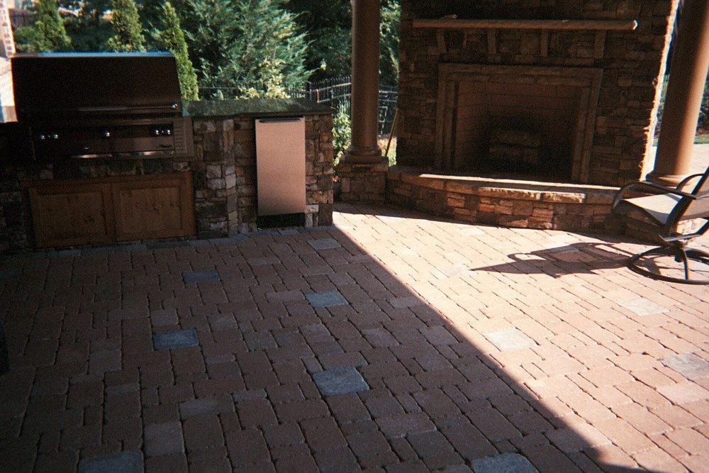 A brick patio with a fireplace and a grill