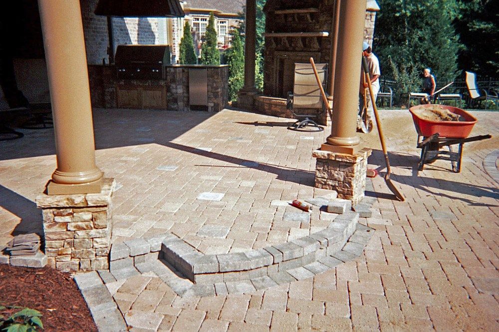 A red wheelbarrow is sitting on a brick patio