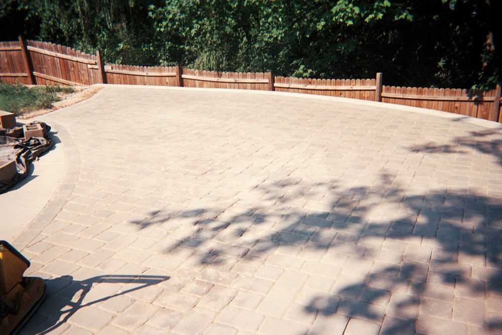 A brick driveway with a wooden fence in the background