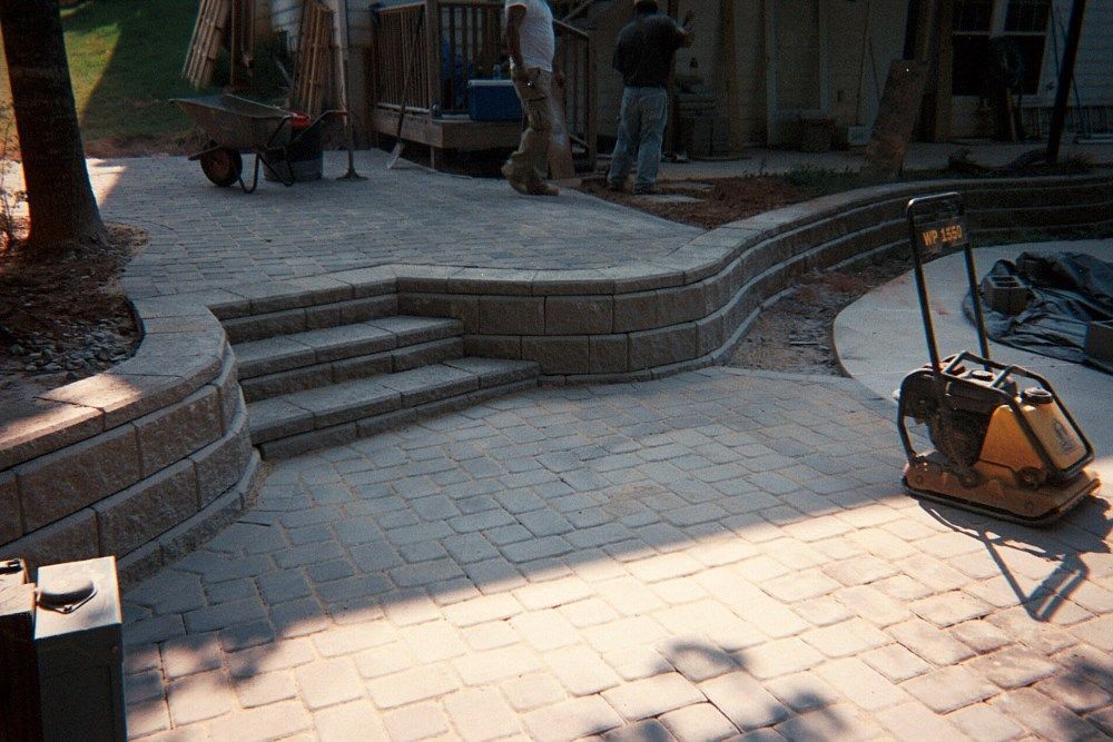 A brick walkway is being built in a backyard.