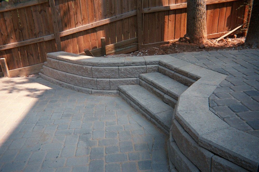 A patio with stairs and a wooden fence in the background.