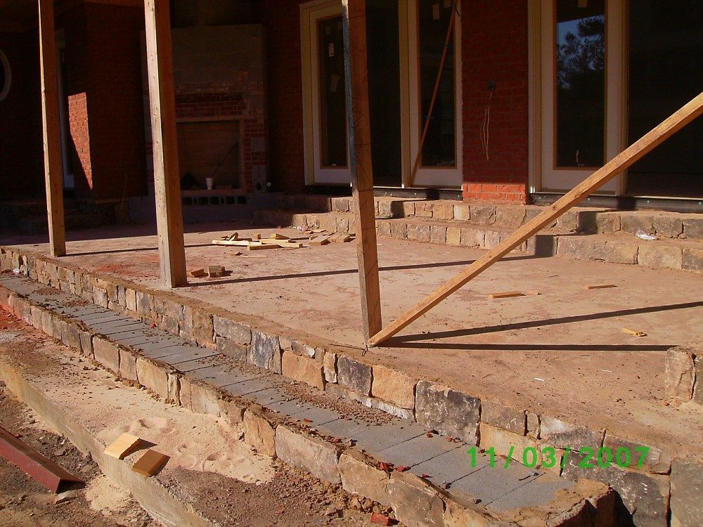 A picture of a brick porch being built on a sunny day