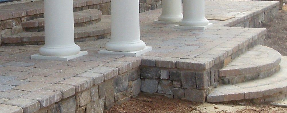 A brick walkway with white columns and steps