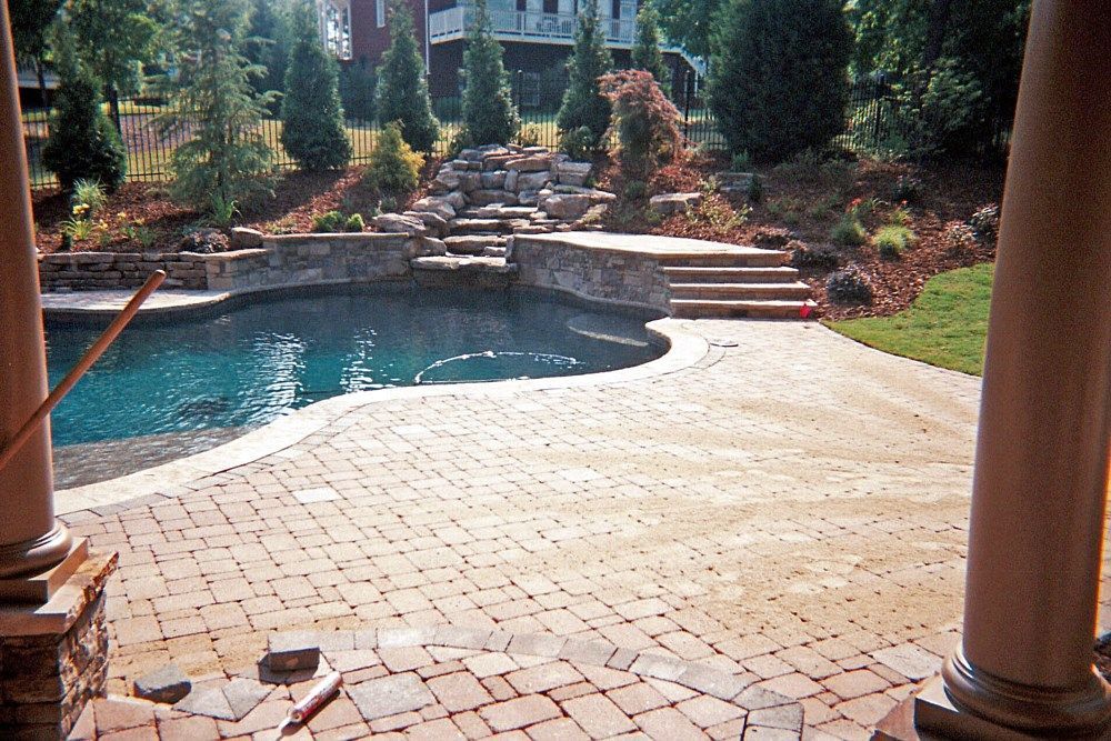 A patio with columns and a pool in the background