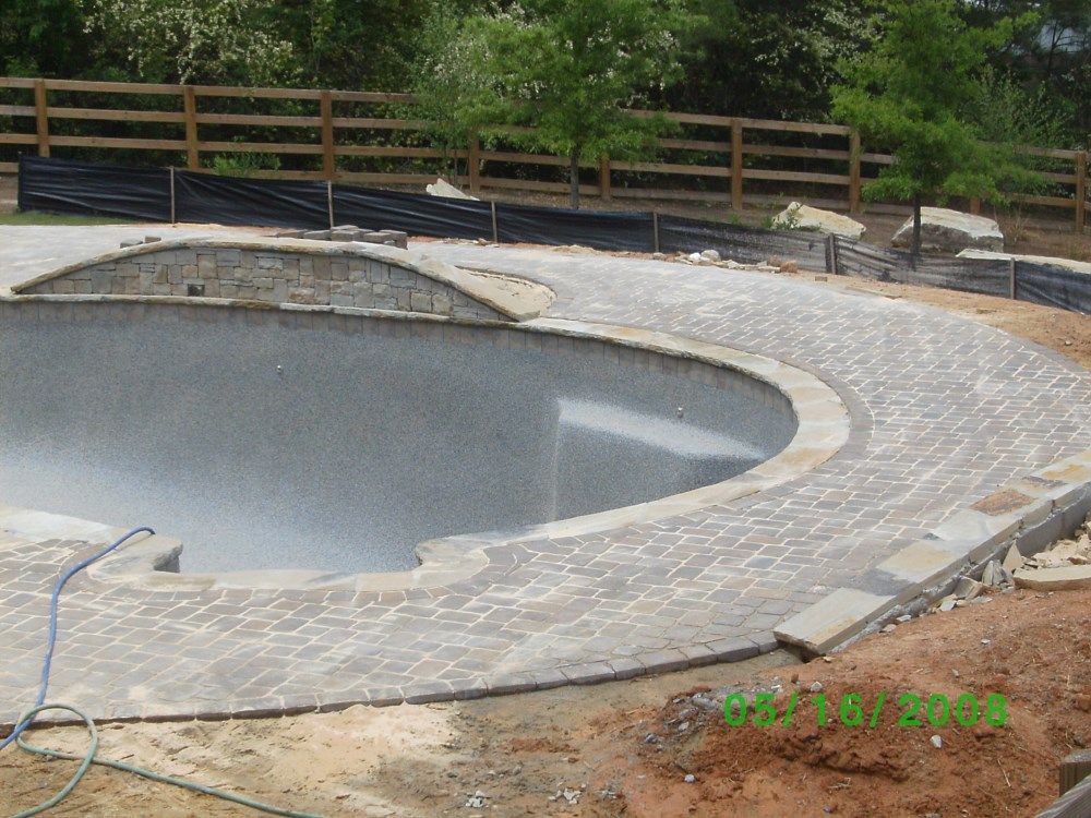 A swimming pool is being built with a wooden fence in the background
