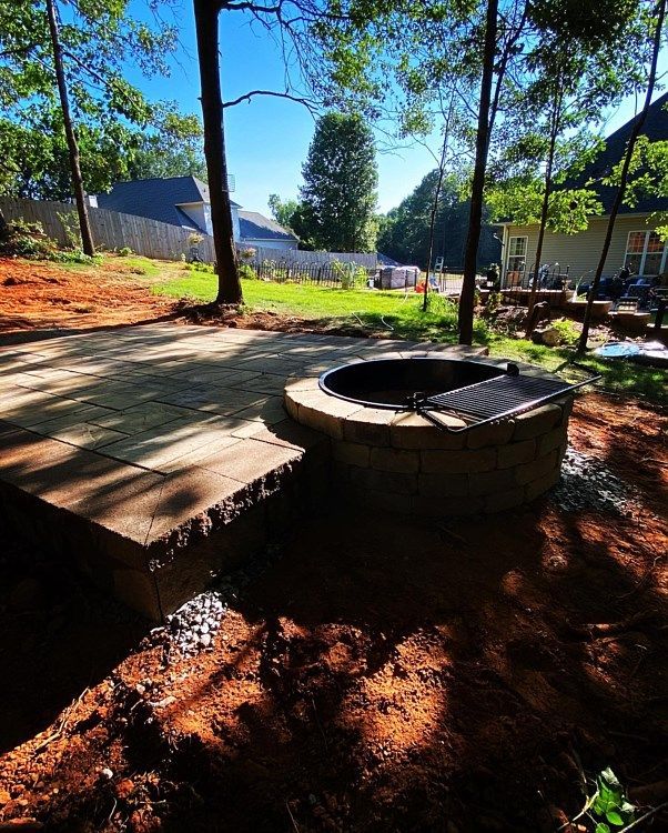 A fire pit is sitting in the middle of a backyard surrounded by trees.