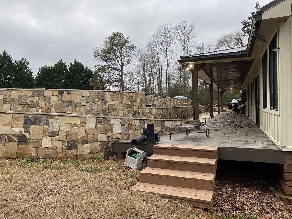 A house with a stone wall and steps leading to it.