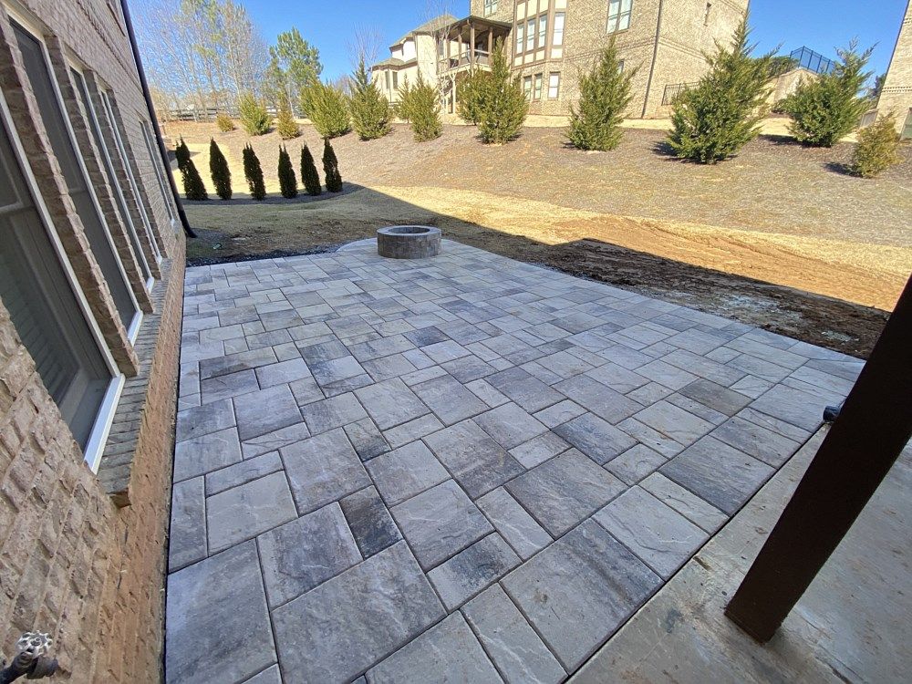 A patio with a fire pit in the backyard of a house.