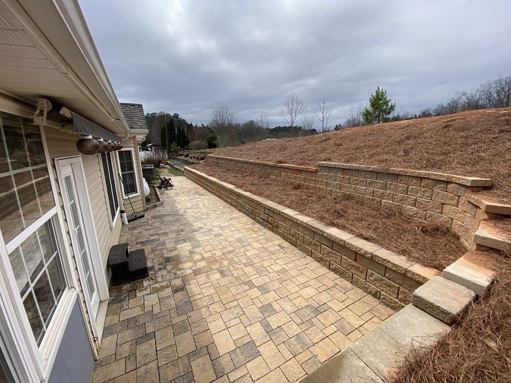 A brick walkway leading to a house with stairs leading up to it.