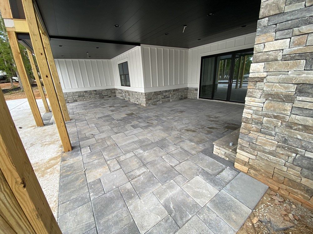 A patio with a stone wall and a black ceiling in front of a house.