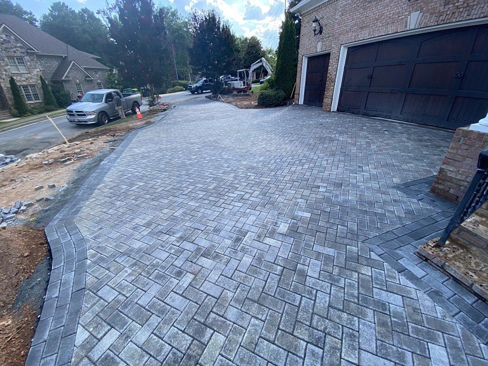 A brick driveway is being built in front of a house.