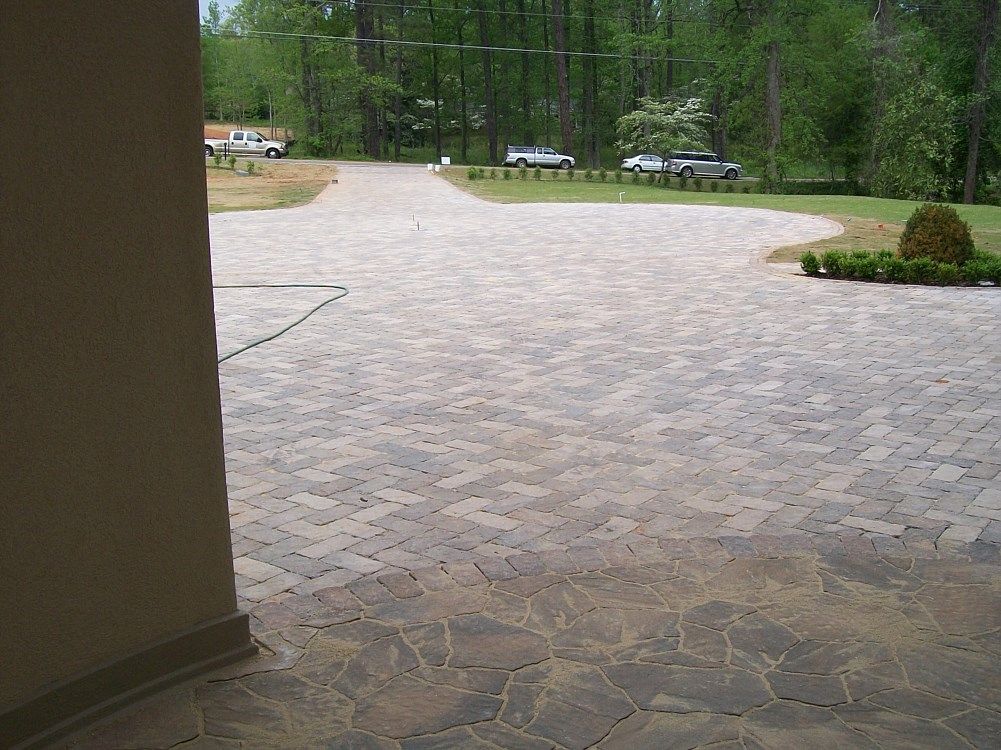 A brick driveway with cars parked on the side of it