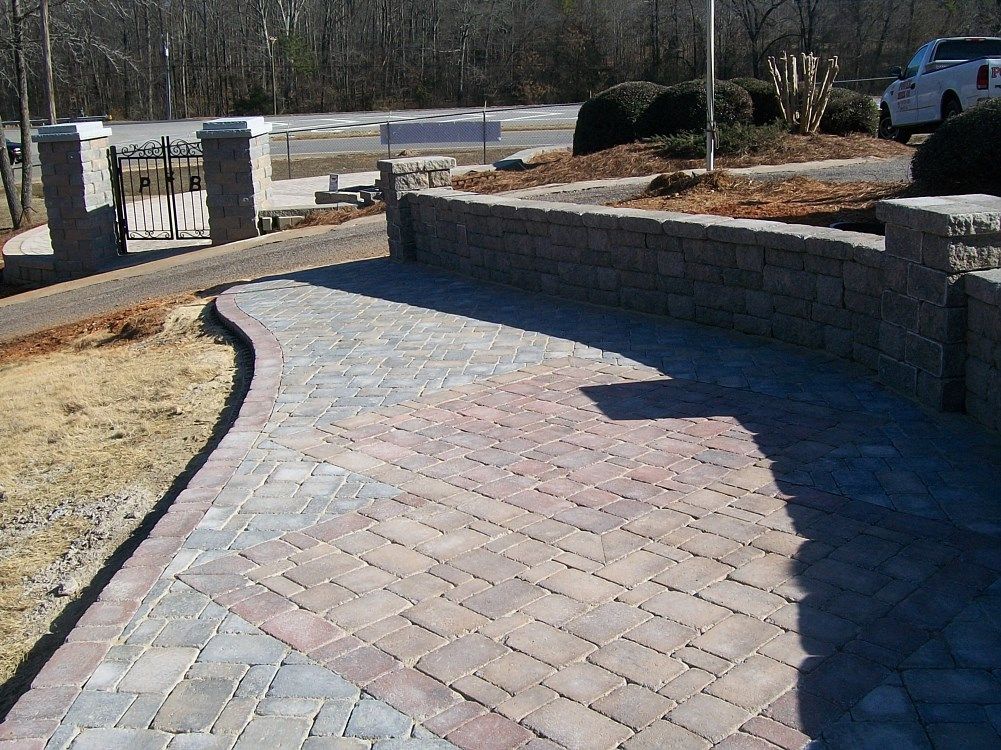 A brick walkway with a stone wall along the side of it