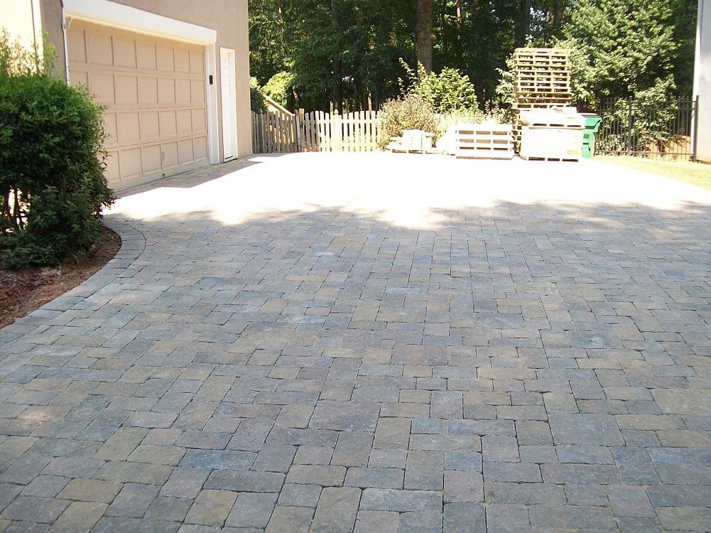 A brick driveway with a garage in the background