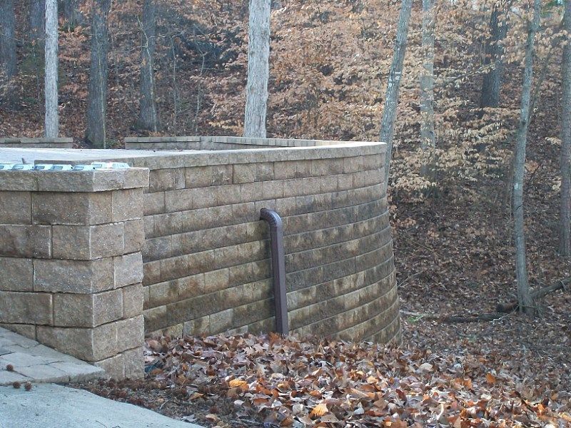 A brick wall with a pipe coming out of it in the woods