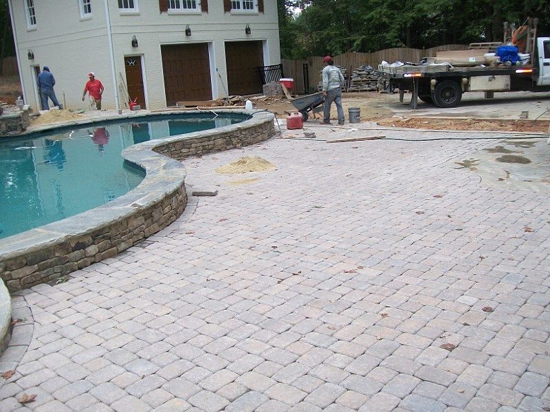 A brick patio with a swimming pool in the background