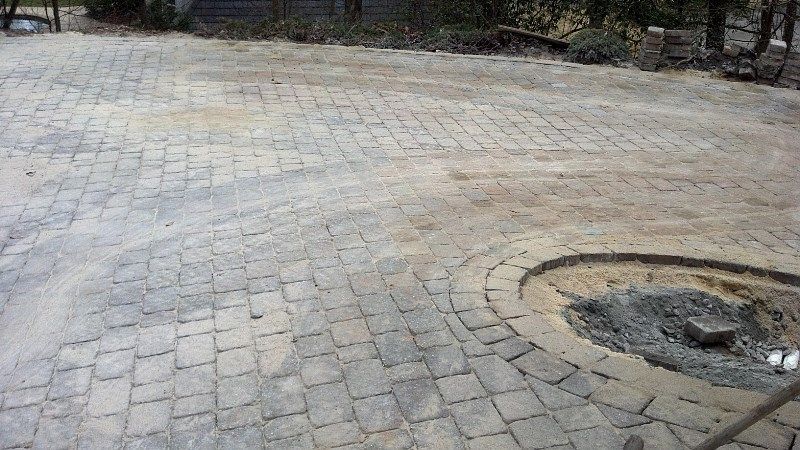 A brick driveway with a fire pit in the middle of it.