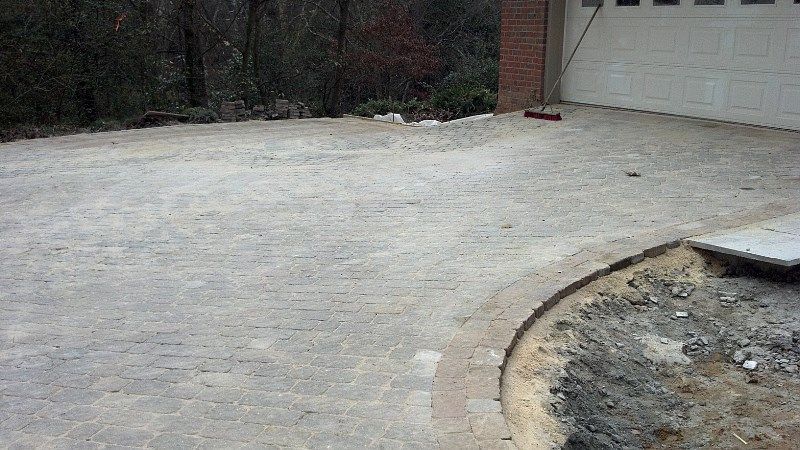 A brick driveway is being built in front of a garage.