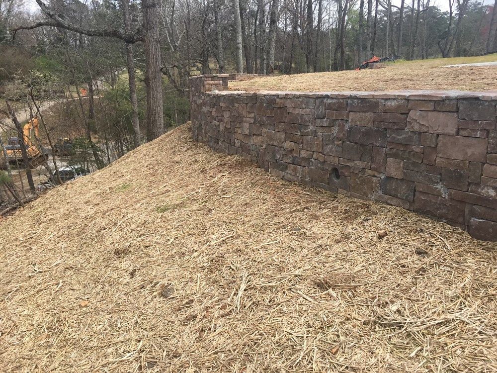 A stone wall is sitting on top of a hill surrounded by trees.