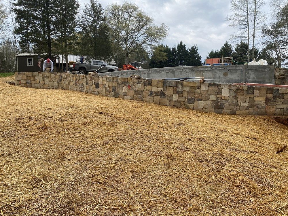 A stone wall is being built in the middle of a field.