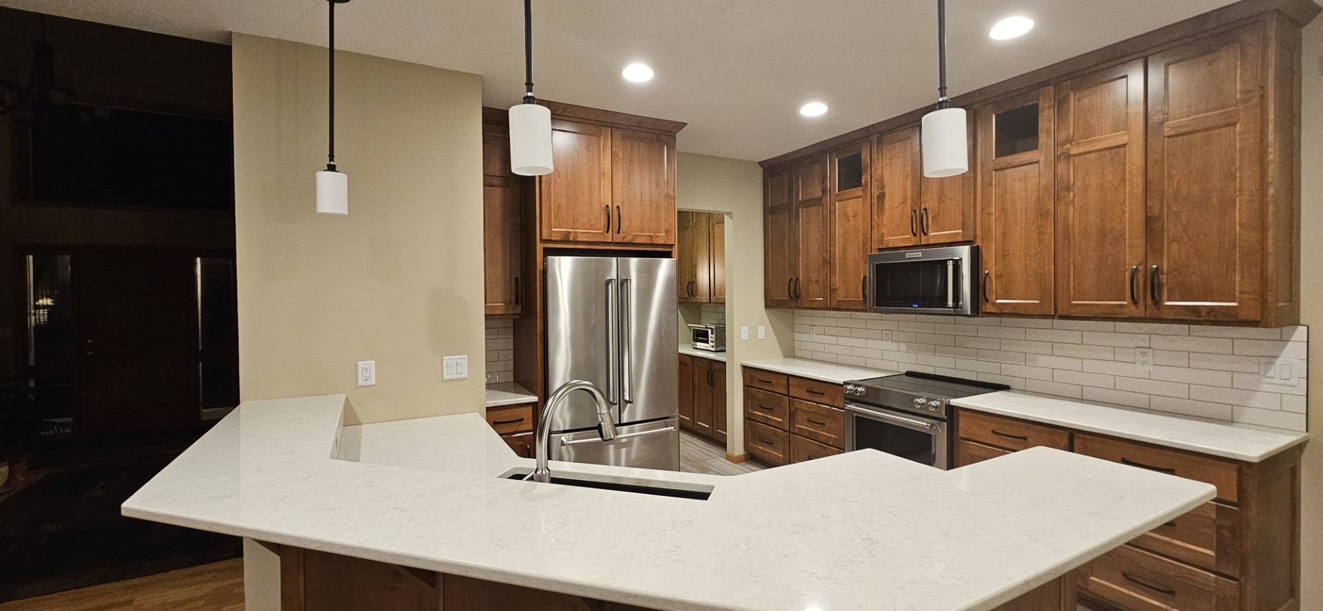 A kitchen with wooden cabinets, stainless steel appliances, and a large island
