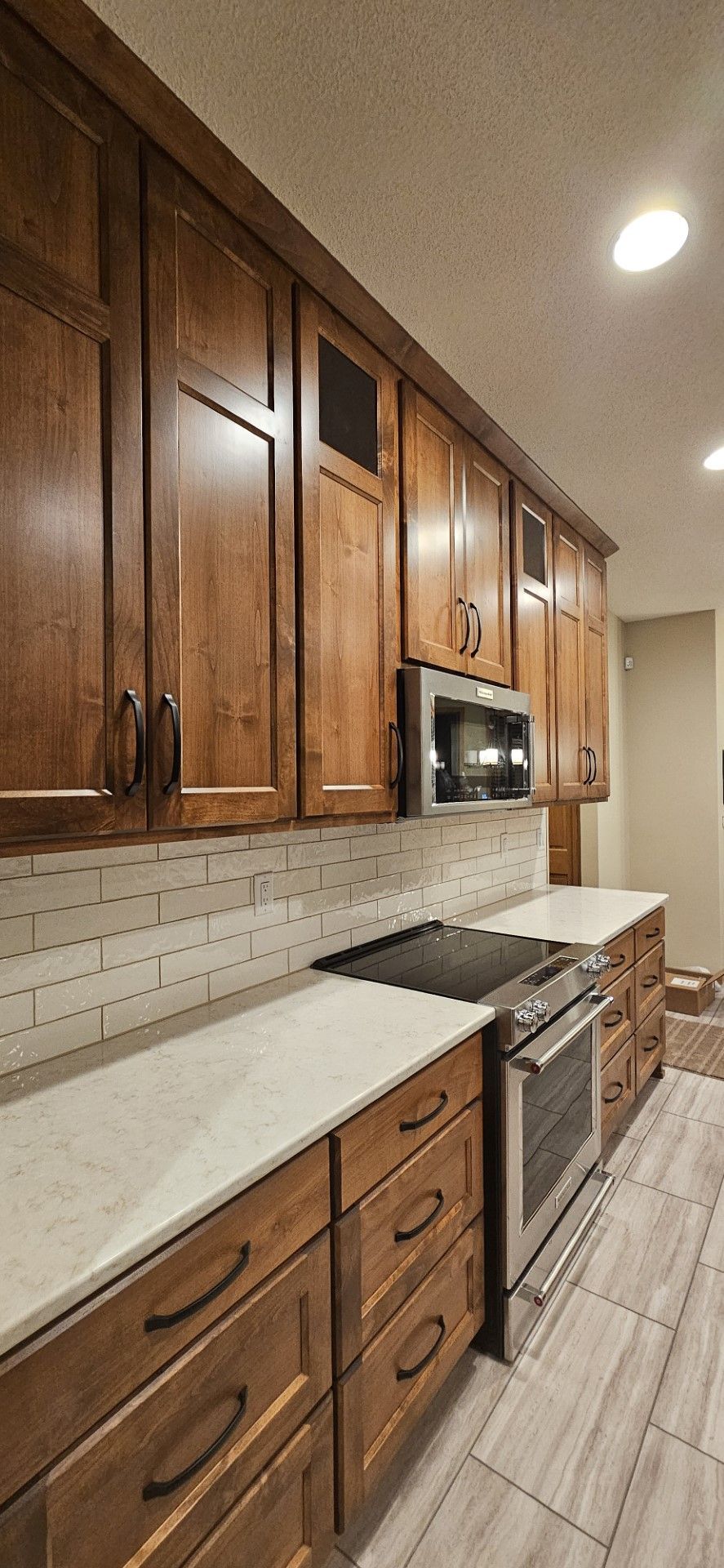 A kitchen with wooden cabinets, stainless steel appliances, and white counter tops