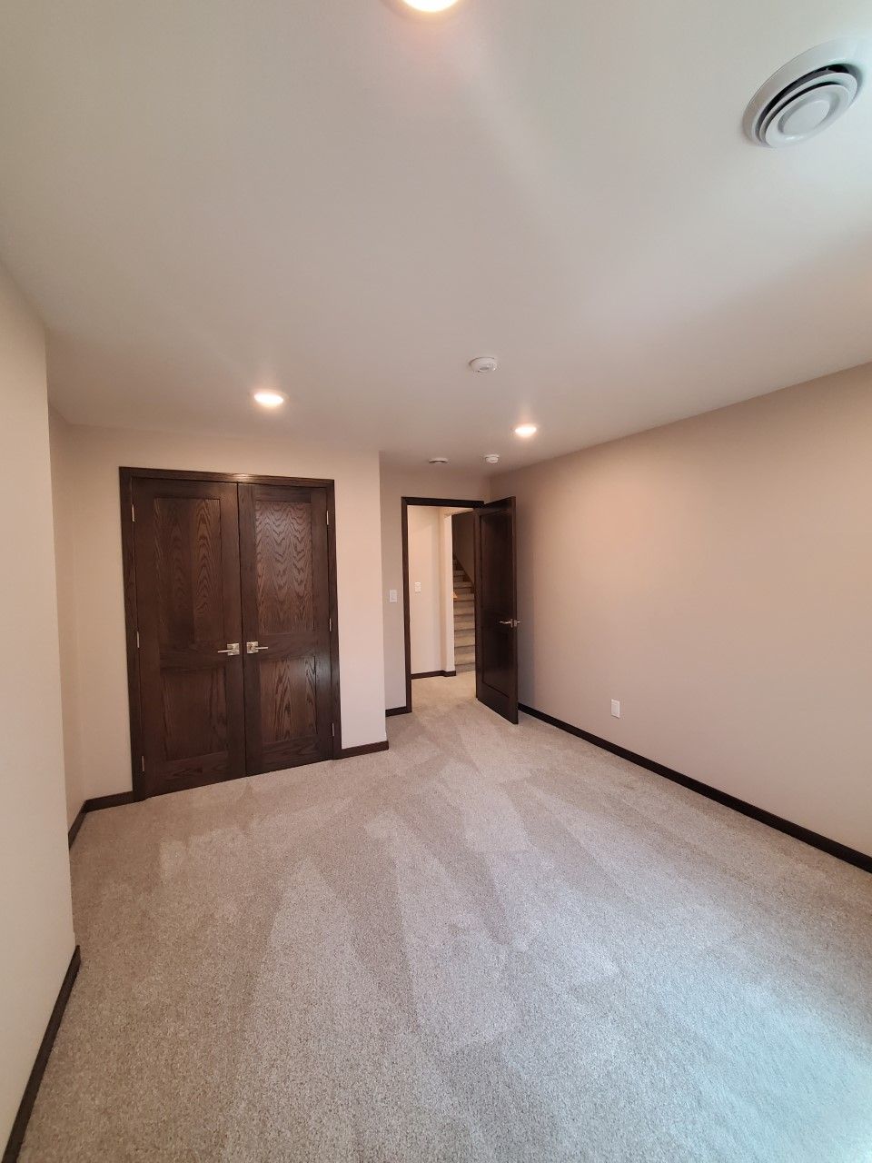 A large empty room with a carpeted floor and a wooden door