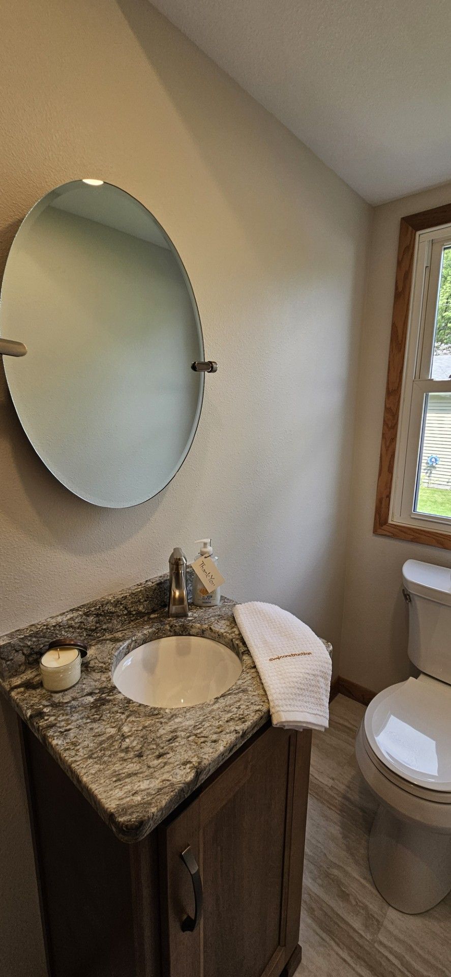 A bathroom with a sink, toilet, mirror and window