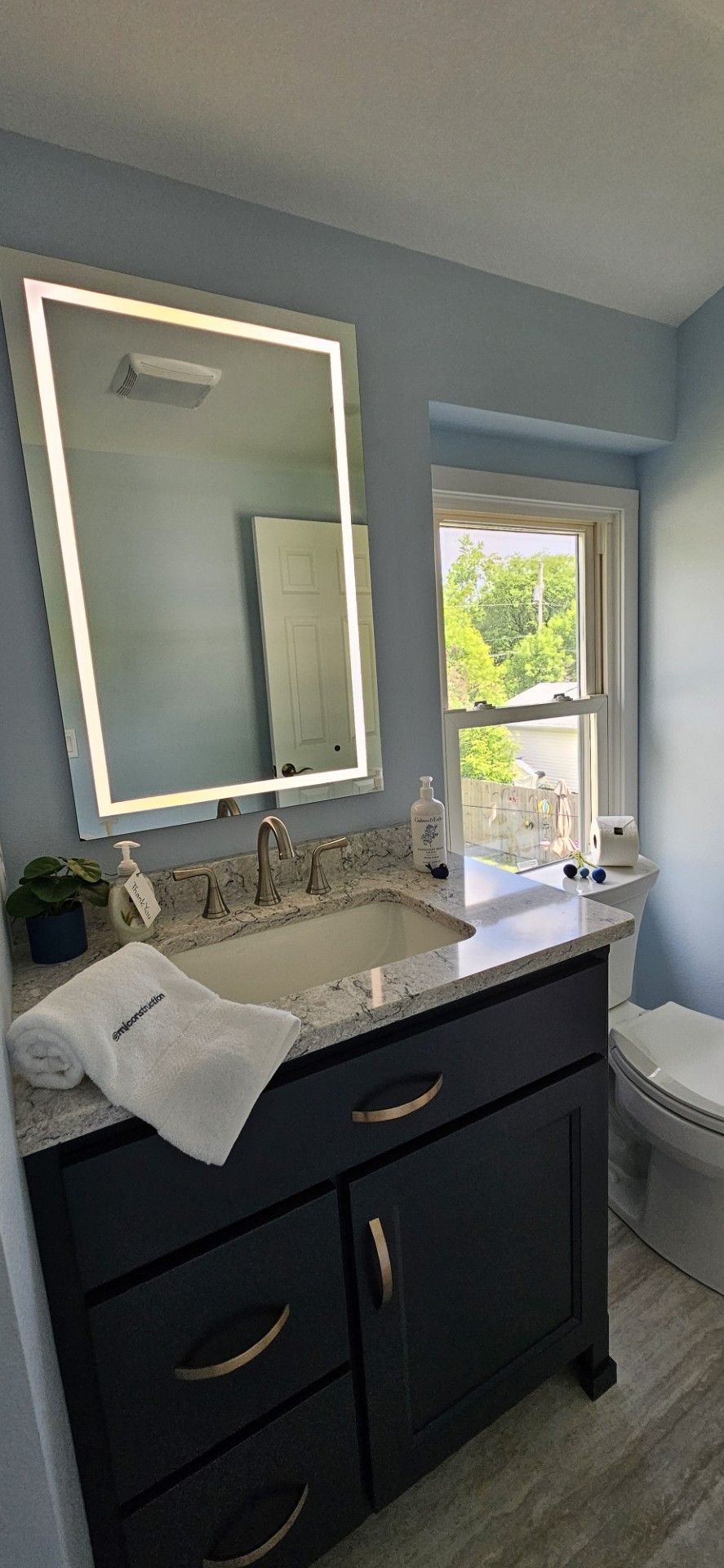 A bathroom with a sink, toilet, mirror and window
