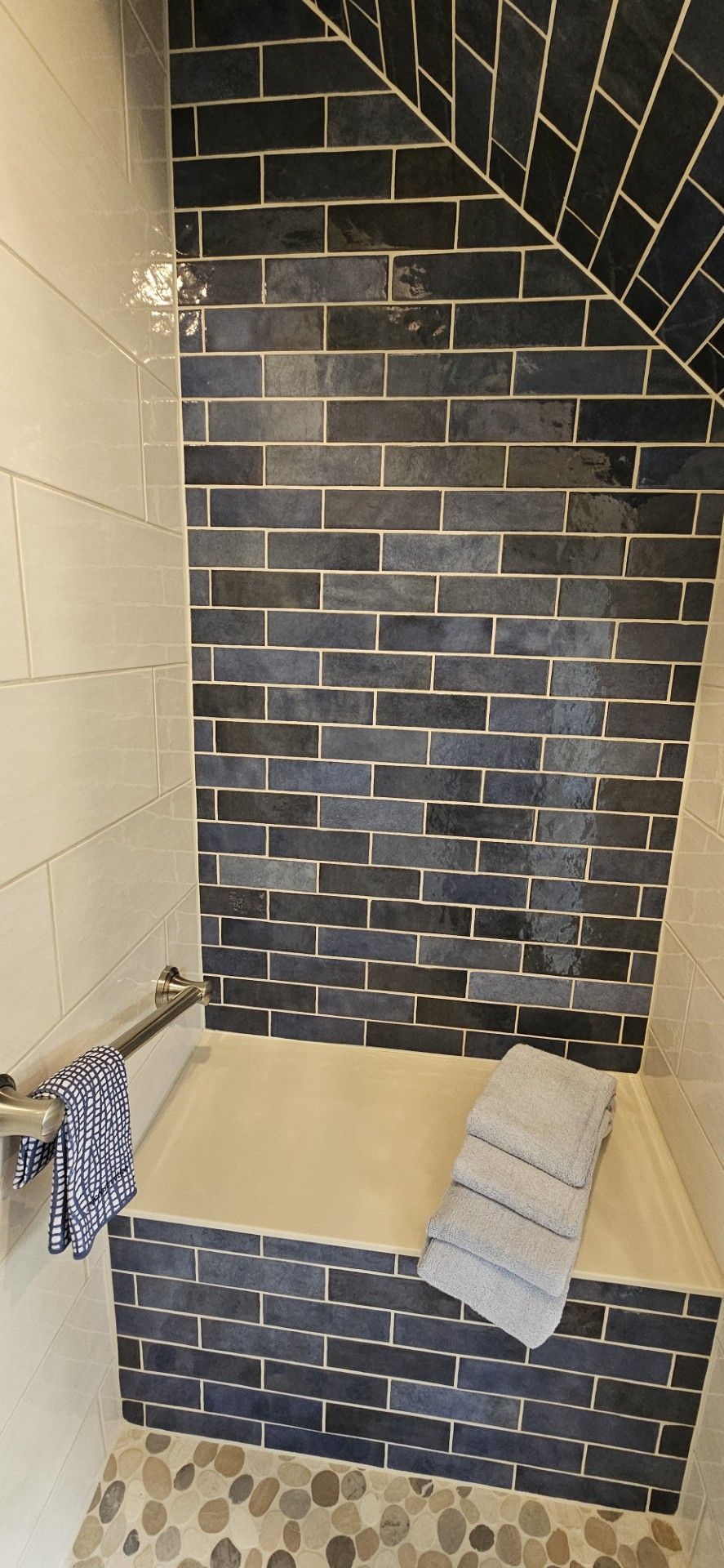 A bathroom with a shower stall and a brick wall