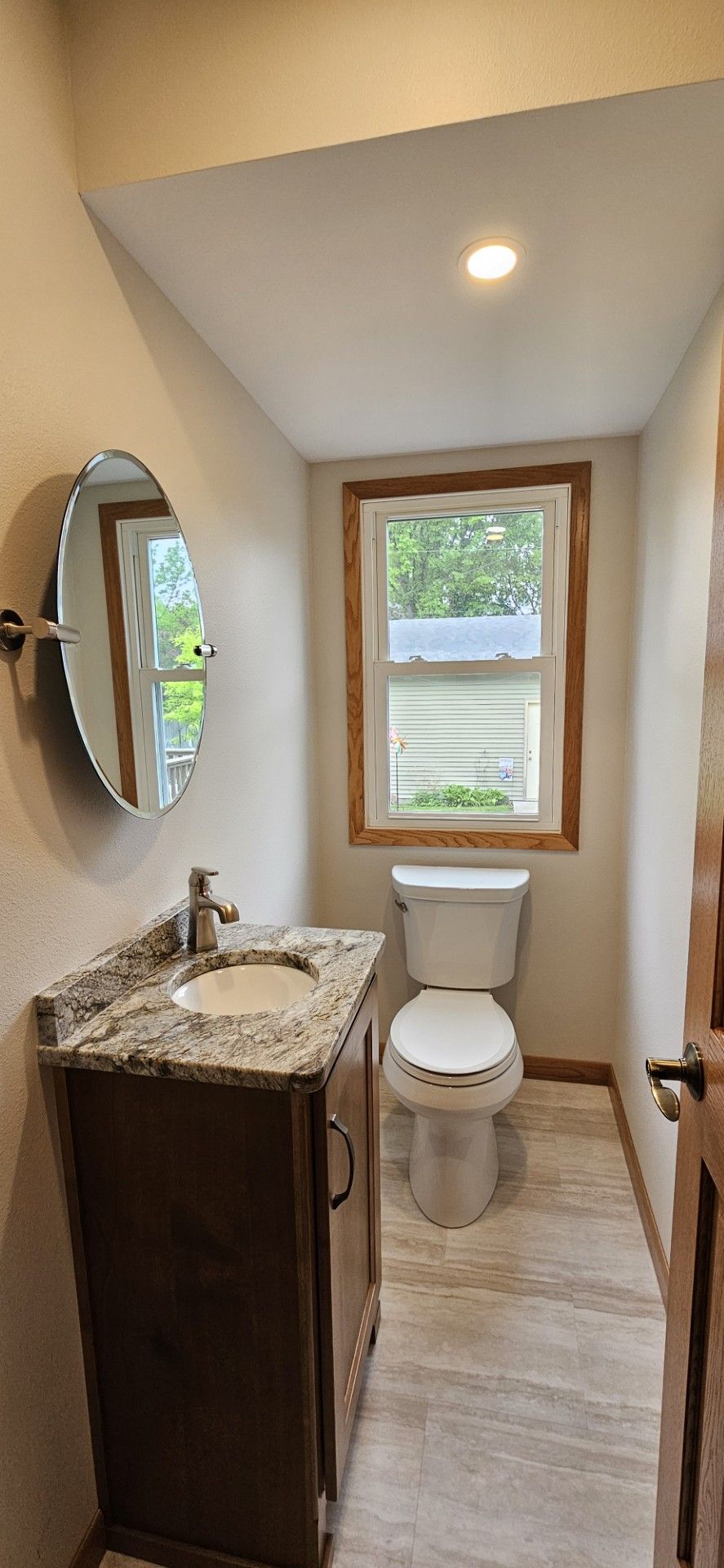 A bathroom with a sink, toilet, mirror and window