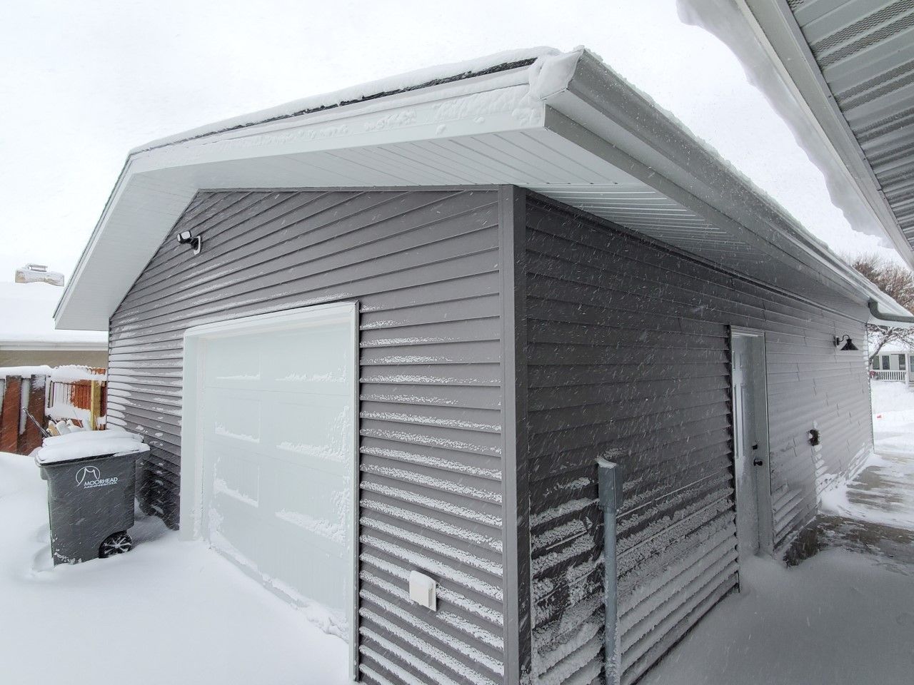 A garage with a white door is covered in snow