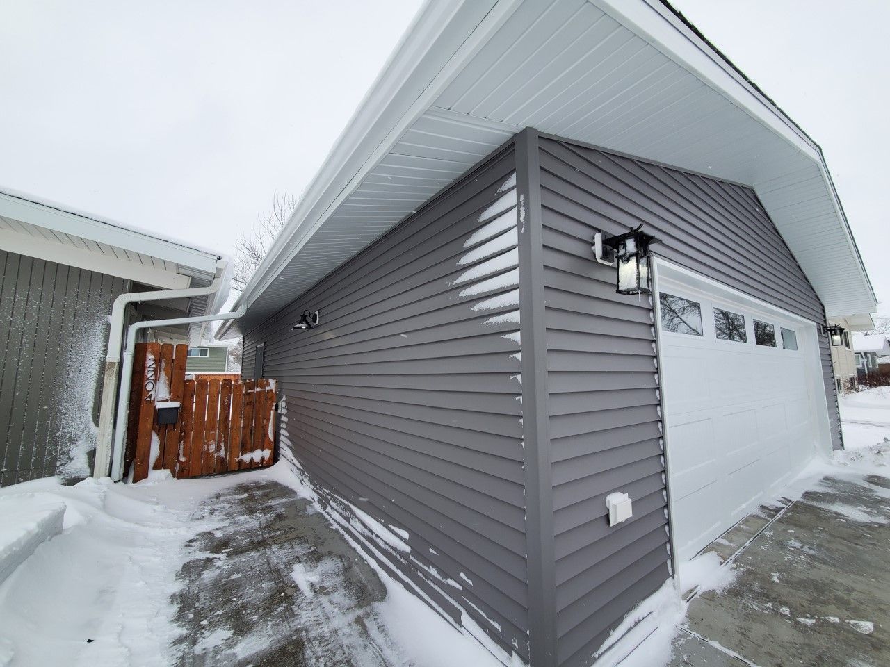 A garage with a white door is covered in snow