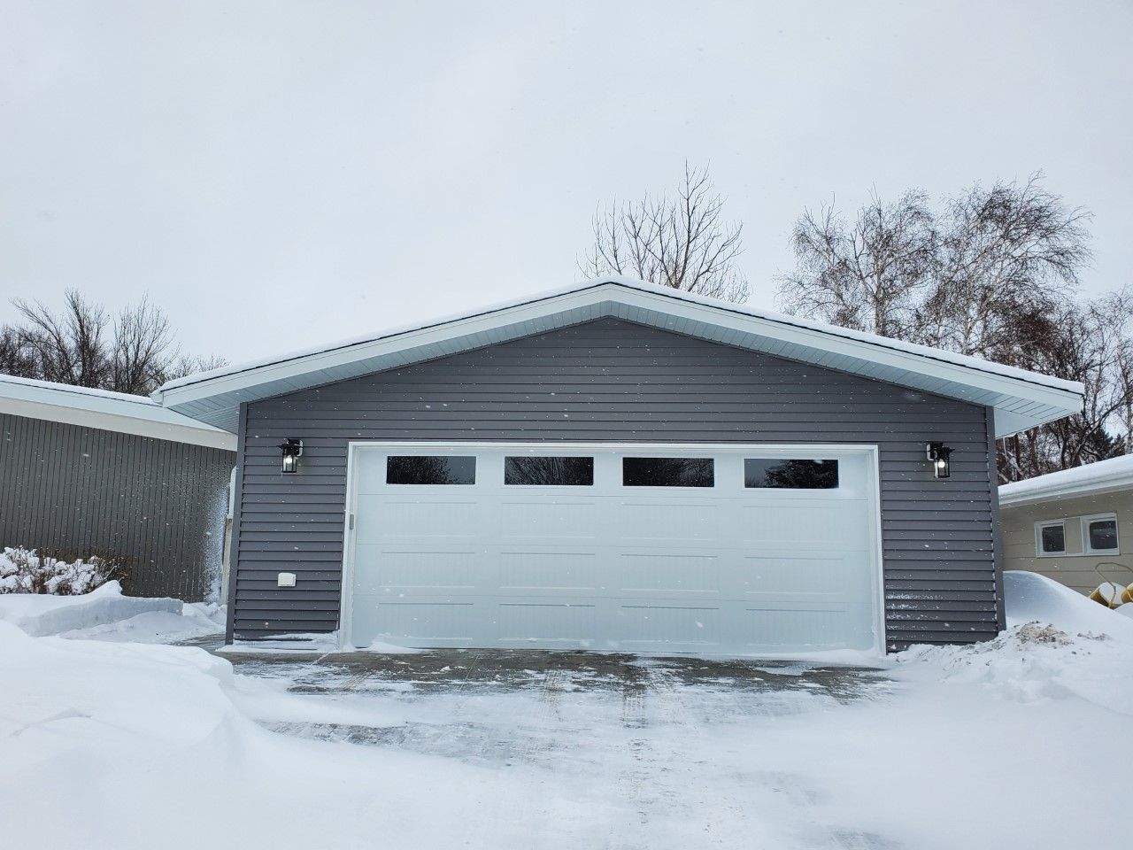 A garage with a white door is covered in snow