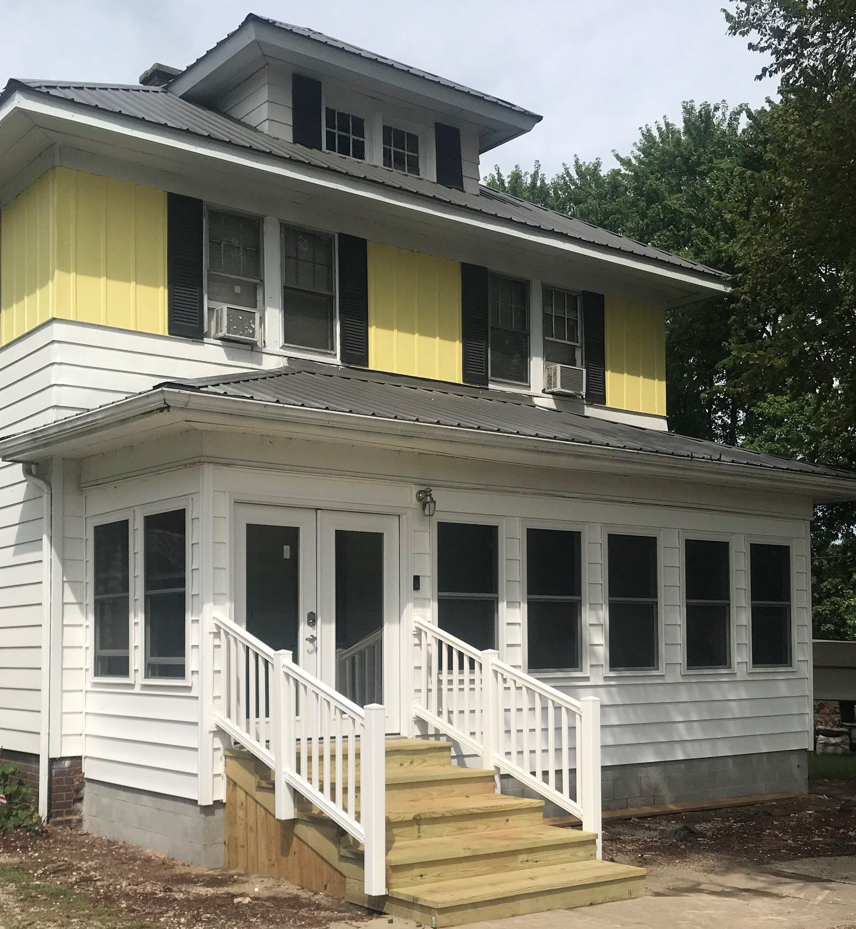 A white house with yellow siding and black shutters