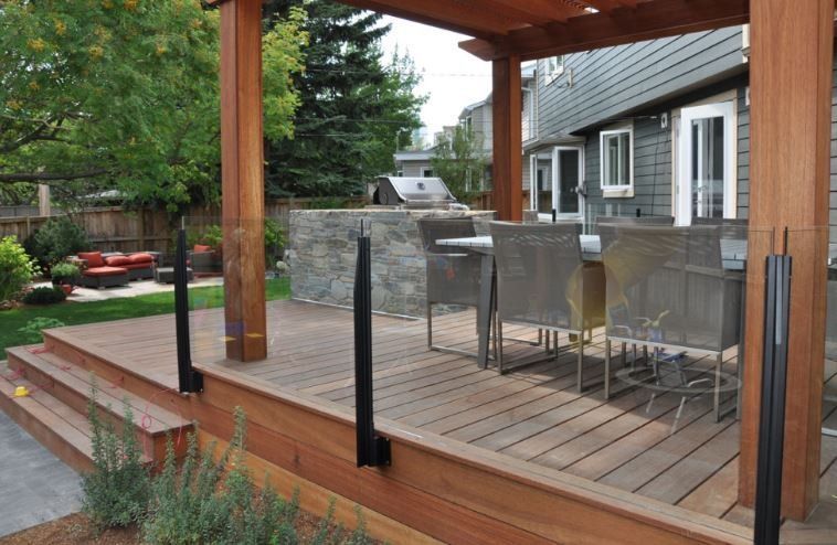 Wooden deck with pergola, seating area, and black metal railings.