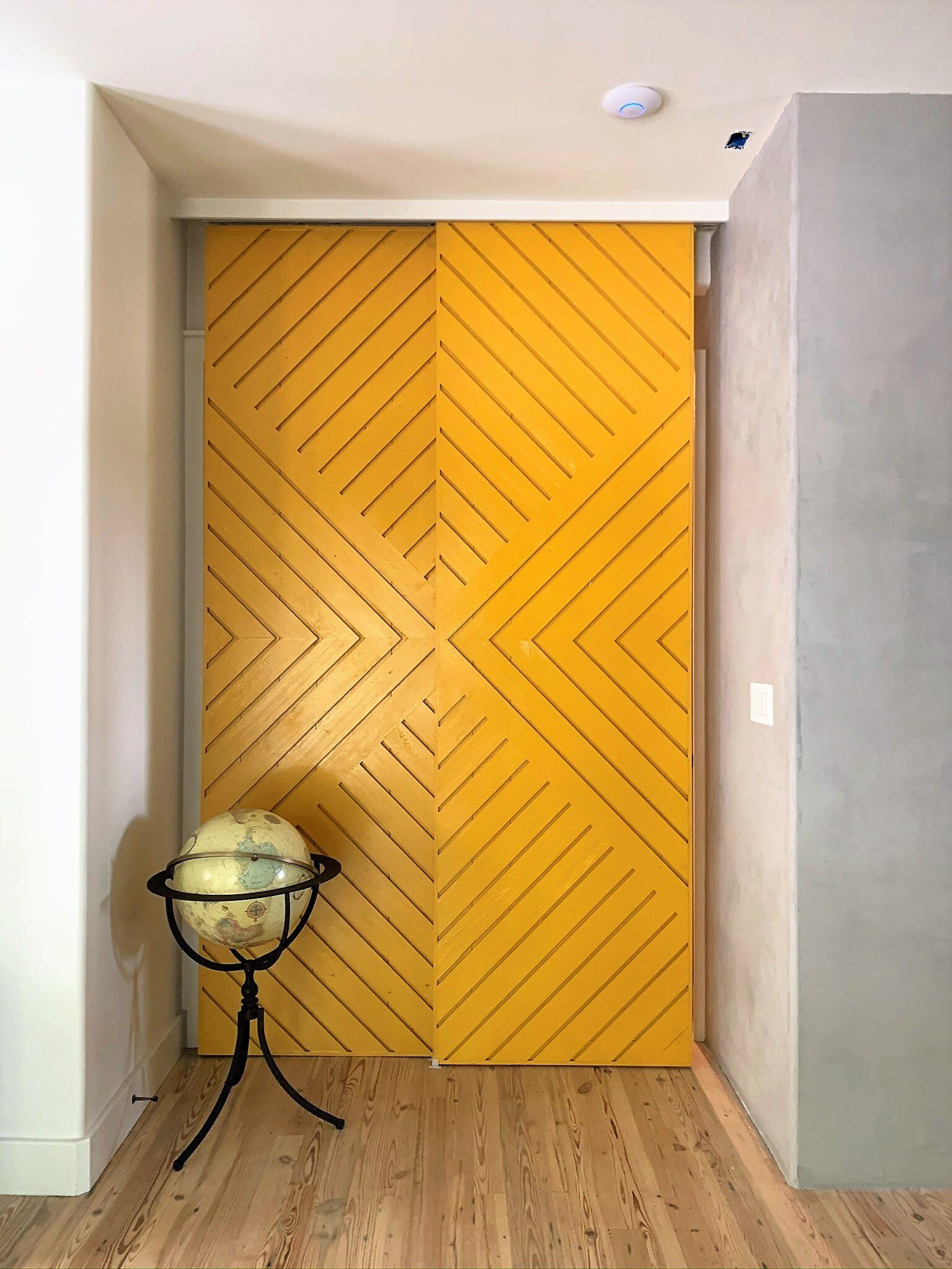 A yellow door with a geometric pattern is in a hallway.