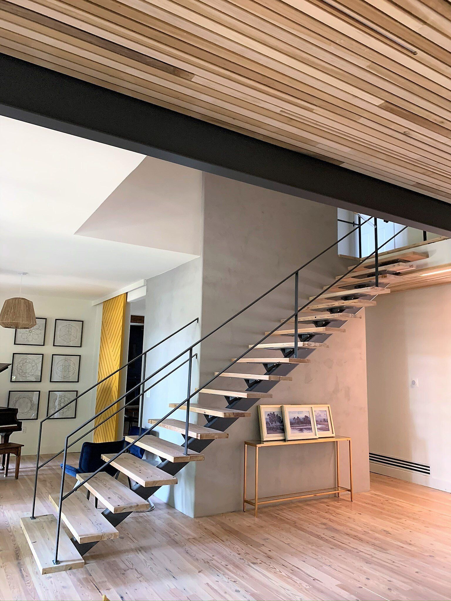 A wooden staircase with a metal railing in a living room.