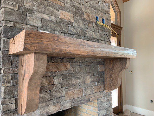 a wooden mantle is sitting on top of a stone fireplace