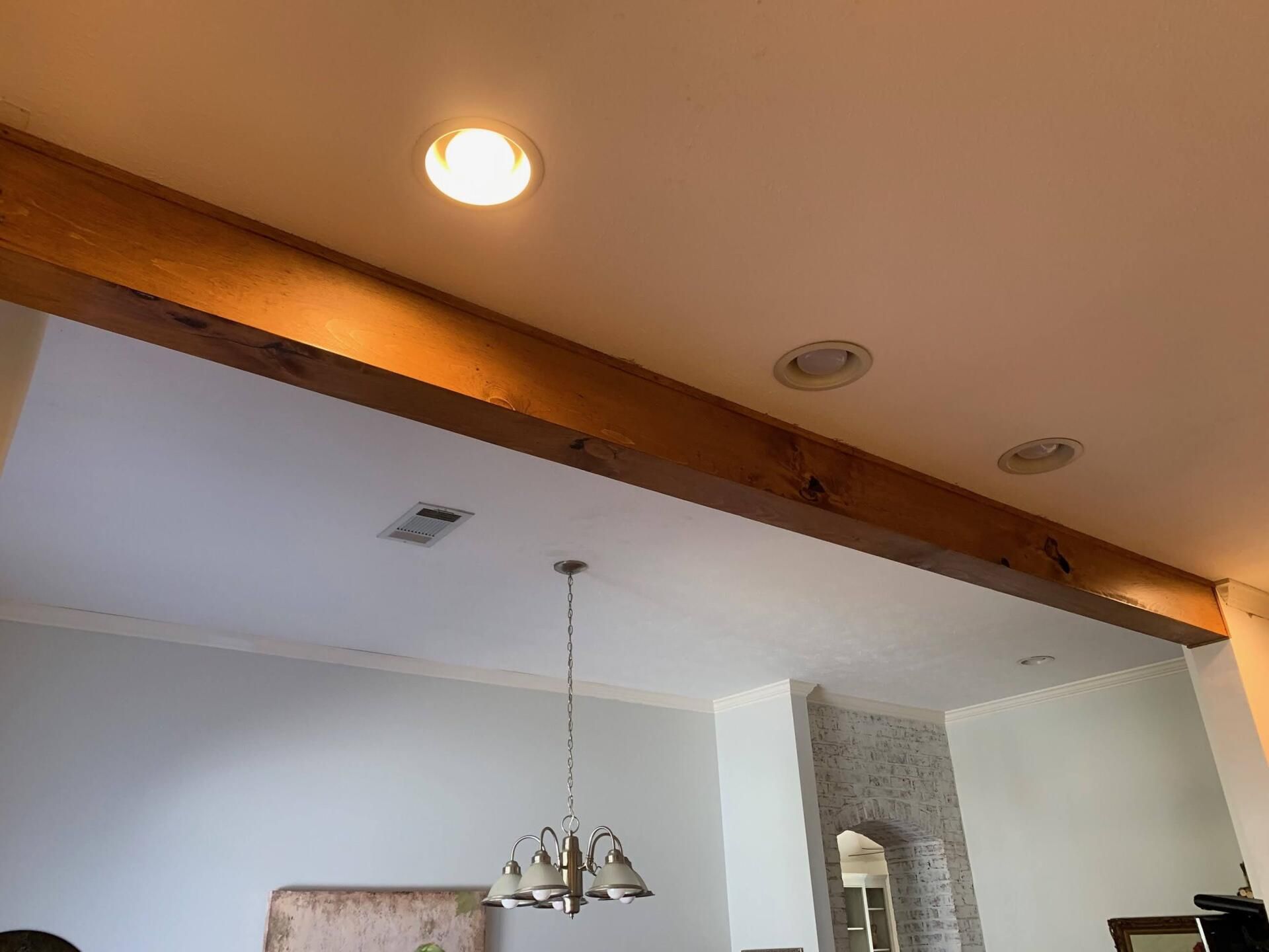 a living room with a wooden beam hanging from the ceiling and a chandelier hanging from the ceiling